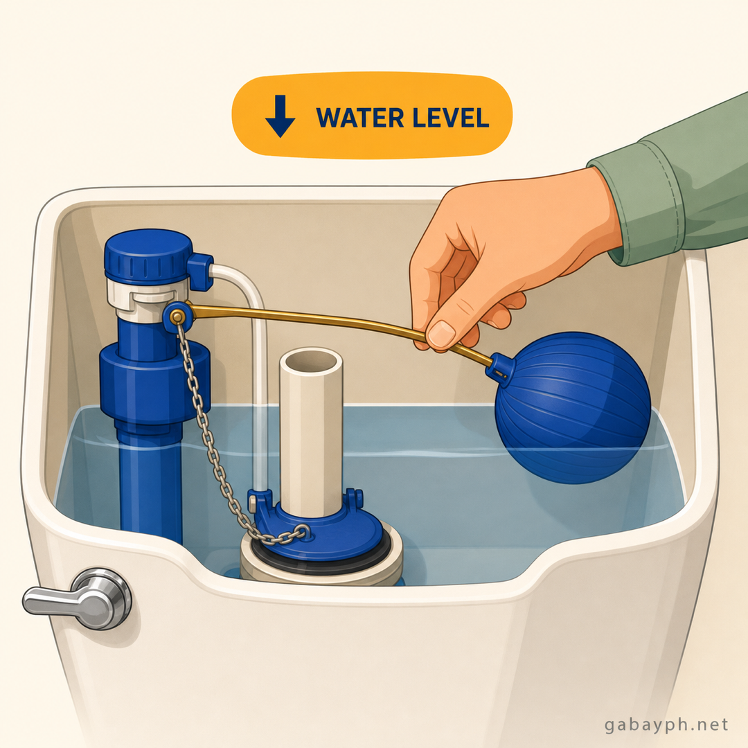 Hand adjusting the toilet float arm to lower the water level