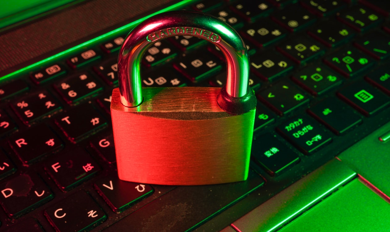 Padlock on a laptop keyboard with red and green lighting representing digital security and fraud prevention