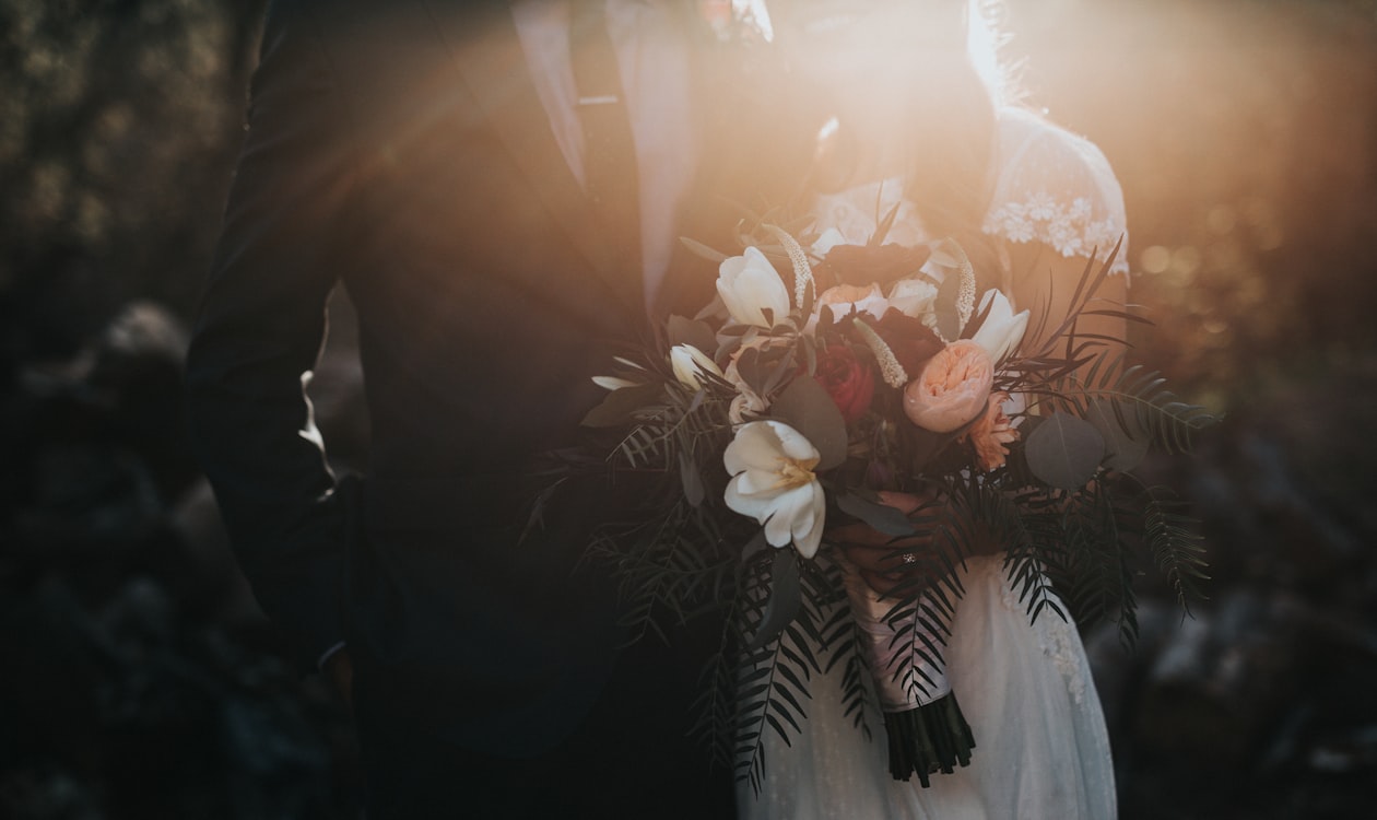 Bride and groom holding a beautiful wedding bouquet at golden hour